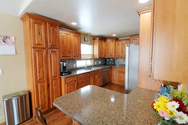 1611 Peosta Ave, Helena, MT 59601 - kitchen featuring a sink, a peninsula, dark wood-type flooring, decorative backsplash, and appliances with stainless steel finishes