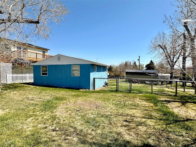 view of home's exterior featuring a lawn, fence, and a gate