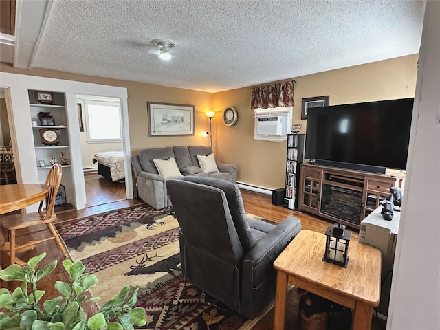 living area featuring a baseboard heating unit, wood finished floors, a textured ceiling, a baseboard radiator, and an AC wall unit