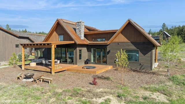 rear view of property featuring metal roof, a deck, and a chimney