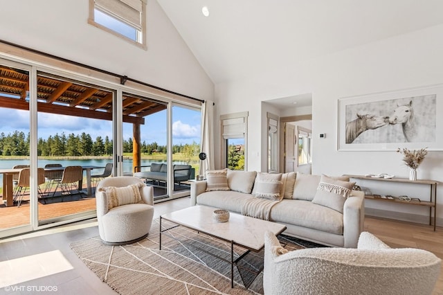 living room with a water view, a wealth of natural light, high vaulted ceiling, and wood finished floors