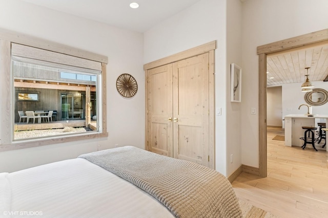 bedroom with a sink, baseboards, and light wood-type flooring