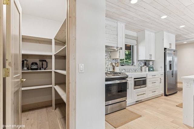 kitchen featuring light countertops, stainless steel appliances, light wood-type flooring, and wood ceiling
