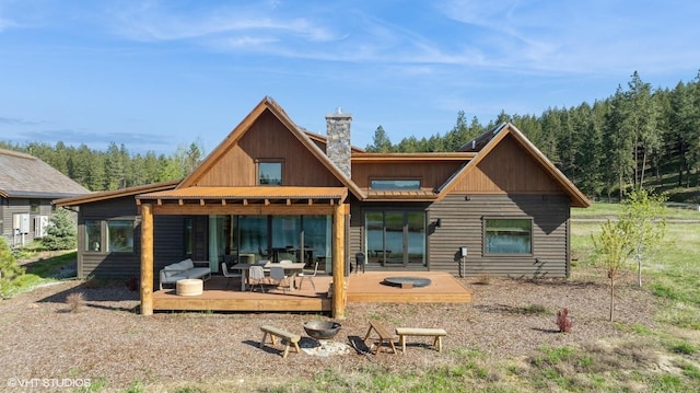 rear view of house with a wooded view, a chimney, and a deck