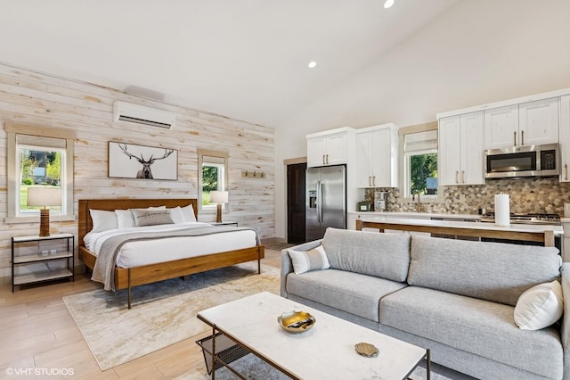 bedroom featuring multiple windows, high vaulted ceiling, stainless steel refrigerator with ice dispenser, wooden walls, and a wall unit AC