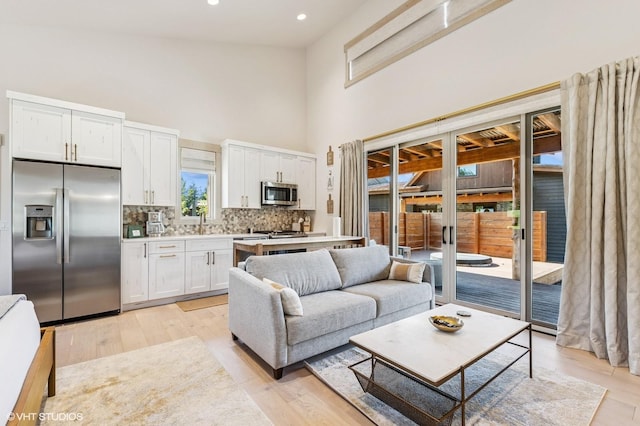 living area with light wood-style flooring, a high ceiling, and recessed lighting