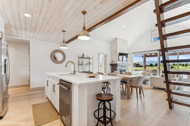 kitchen featuring hanging light fixtures, a sink, beam ceiling, white cabinetry, and appliances with stainless steel finishes