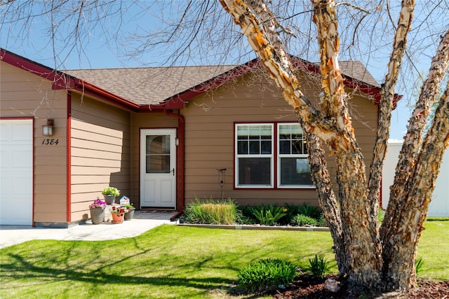 view of front of property with roof with shingles, an attached garage, and a front yard