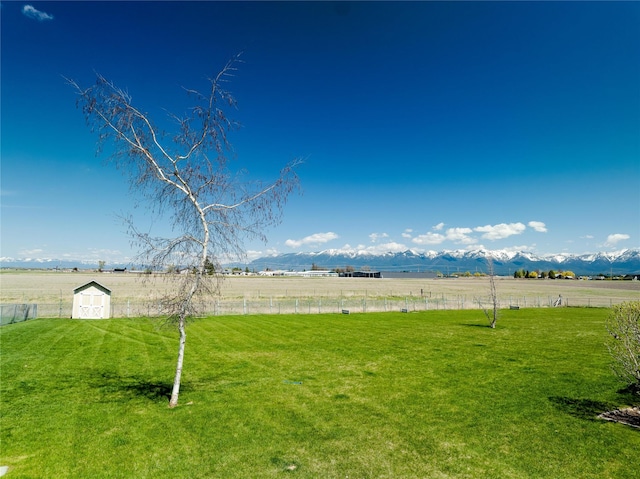 view of yard featuring a rural view, an outdoor structure, and fence