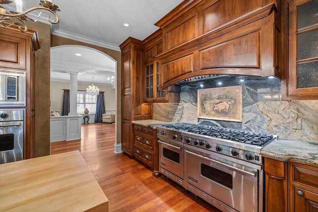 305 Columbia Ave, Whitefish, MT 59937 - kitchen with stainless steel appliances, ornate columns, crown molding, decorative backsplash, and arched walkways