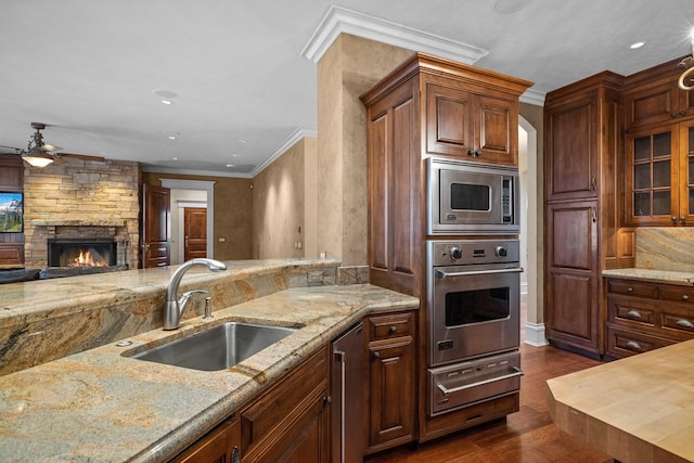 305 Columbia Ave, Whitefish, MT 59937 - kitchen featuring appliances with stainless steel finishes, a warming drawer, a ceiling fan, a fireplace, and light stone counters