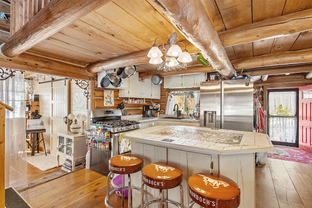 1441 Bonanza Dr, Sula, MT 59871 - kitchen with stainless steel appliances, light wood-style flooring, a sink, wooden ceiling with exposed beams, and a center island