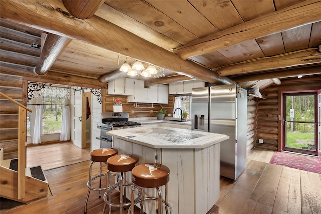 1441 Bonanza Dr, Sula, MT 59871 - kitchen featuring stainless steel appliances, wooden ceiling with exposed beams, rustic walls, light wood-style floors, and healthy amount of natural light