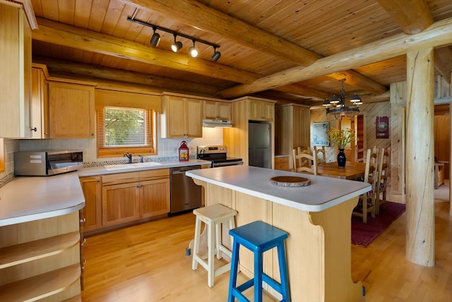 662 S Foys Lake Dr, Kalispell, MT 59901 - kitchen with stainless steel appliances, under cabinet range hood, light wood-style floors, a wooden ceiling with exposed beams, and track lighting