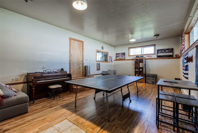 recreation room with a textured ceiling and wood finished floors