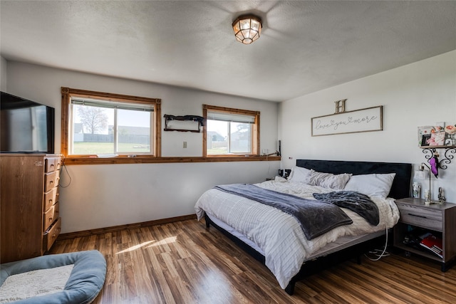 bedroom featuring wood finished floors, baseboards, and multiple windows