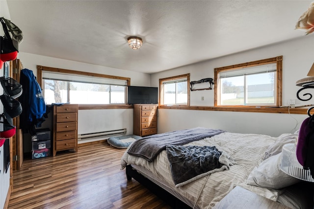bedroom with wood finished floors and a baseboard heating unit
