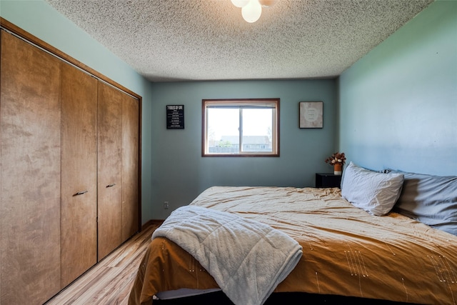 bedroom featuring light wood finished floors, a closet, and a textured ceiling