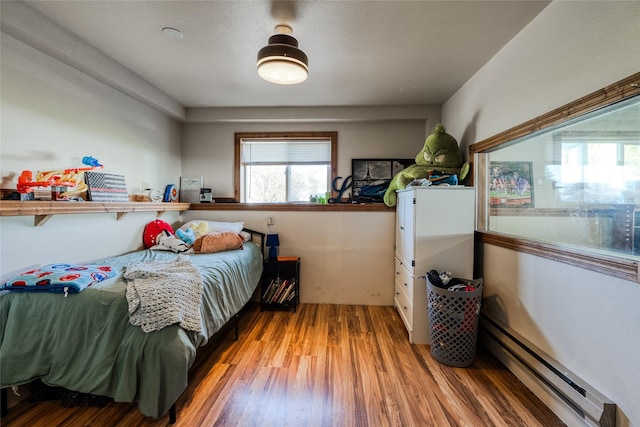 bedroom featuring wood finished floors and baseboard heating