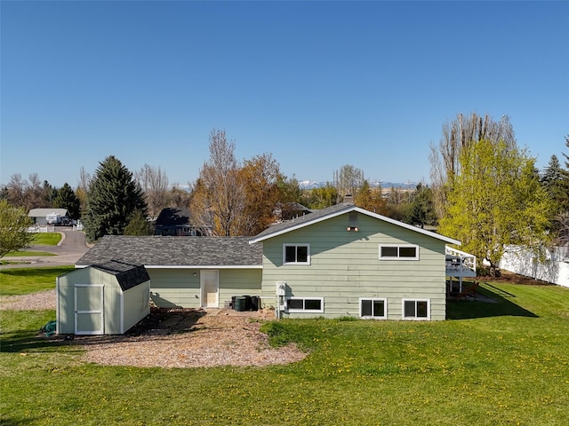rear view of property featuring a yard, a deck, an outbuilding, and a shed
