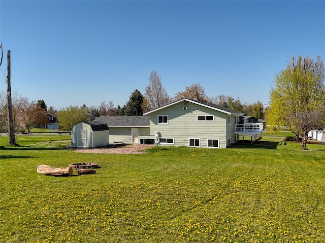 rear view of property with a storage shed, an outbuilding, a fire pit, a wooden deck, and a yard