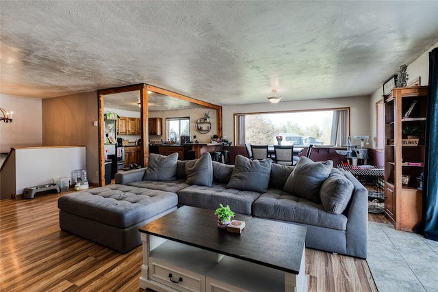 living room featuring light wood finished floors, a chandelier, and a textured ceiling