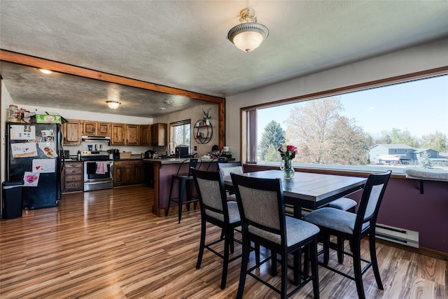 dining area featuring a baseboard heating unit and wood finished floors