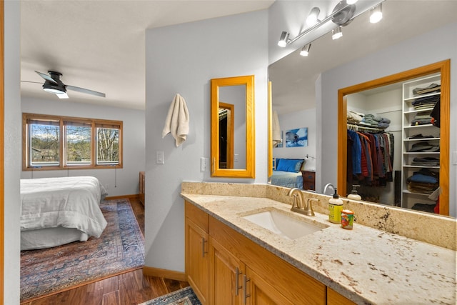 bathroom featuring wood finished floors, vanity, ensuite bath, ceiling fan, and baseboards