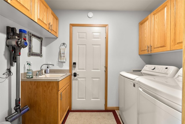 washroom with washer and dryer, cabinet space, and a sink