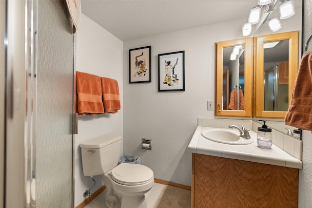 bathroom with baseboards, tile patterned floors, vanity, and toilet