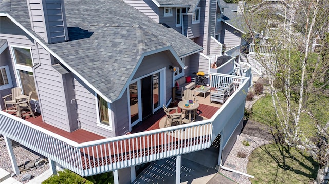exterior space featuring outdoor dining space, a wooden deck, and roof with shingles