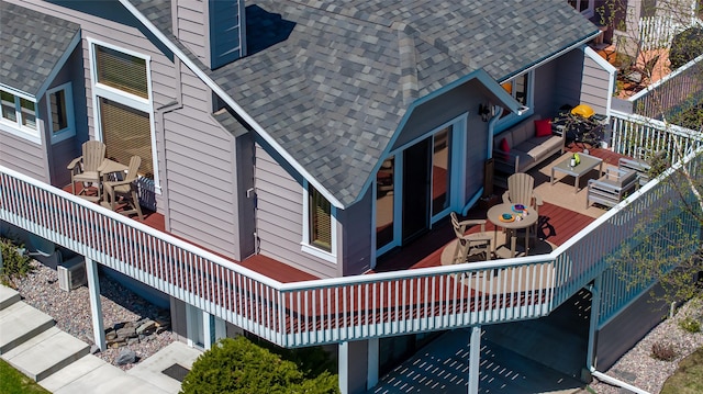 exterior space with a shingled roof, outdoor dining area, and a wooden deck