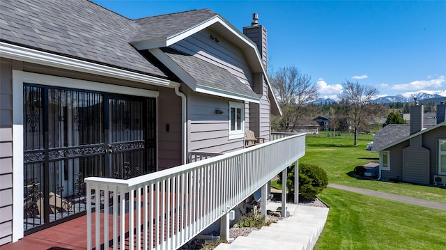 view of side of home featuring a shingled roof, a chimney, and a lawn
