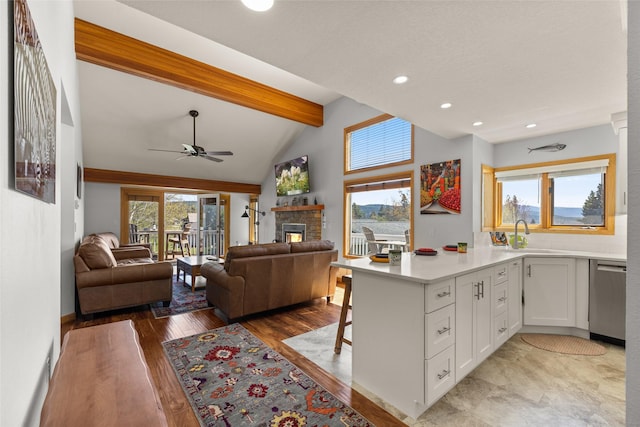 kitchen with a peninsula, a sink, open floor plan, white cabinetry, and dishwasher