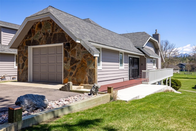 view of front facade with roof with shingles, stone siding, driveway, a front yard, and a chimney