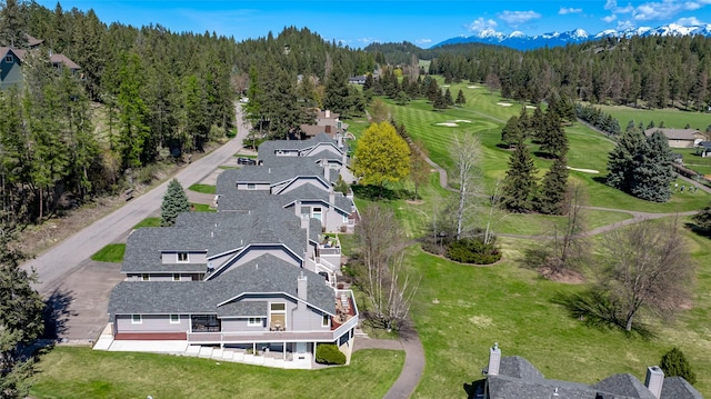 aerial view featuring view of golf course, a wooded view, and a mountain view