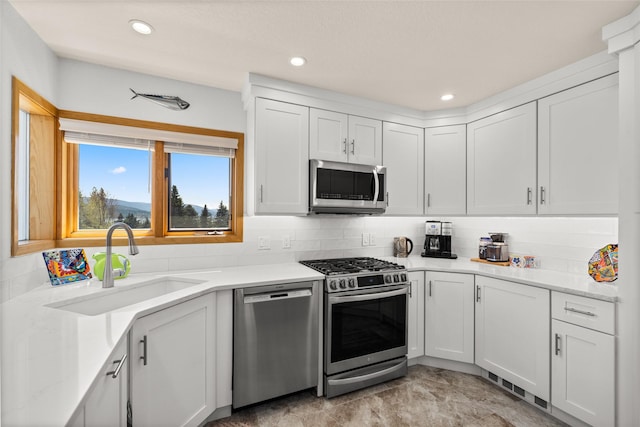 kitchen with a sink, decorative backsplash, light countertops, and appliances with stainless steel finishes