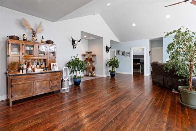 living area featuring lofted ceiling, wood finished floors, a dry bar, ceiling fan, and baseboards