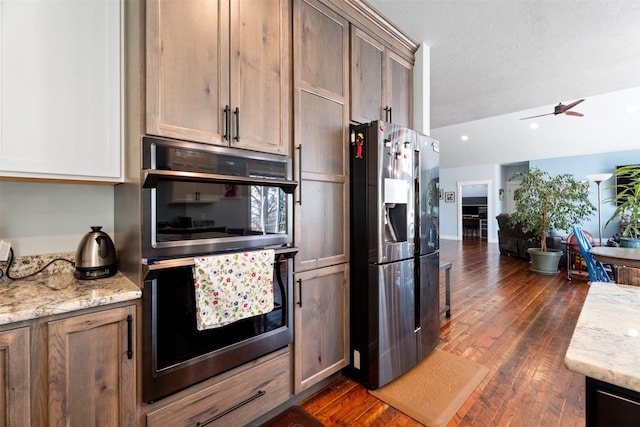 kitchen featuring stainless steel fridge with ice dispenser, open floor plan, dark wood-type flooring, light stone countertops, and ceiling fan