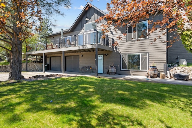 rear view of property with a lawn, board and batten siding, an attached garage, a patio, and a balcony