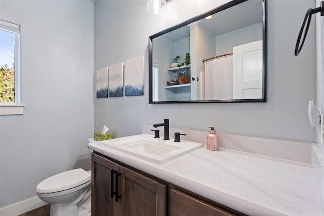 bathroom with vanity, toilet, and baseboards