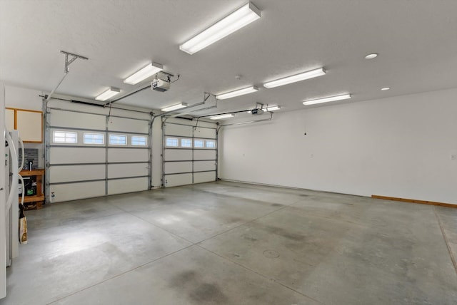 garage with fridge, a garage door opener, and recessed lighting