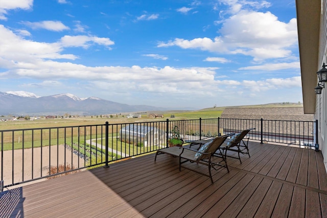 deck with a yard, a rural view, outdoor dining space, and a mountain view