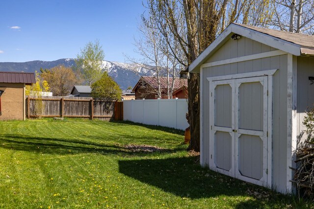 view of yard featuring a fenced backyard, a mountain view, a shed, and an outbuilding