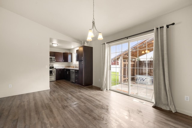 unfurnished dining area with a sink, wood finished floors, visible vents, vaulted ceiling, and an inviting chandelier