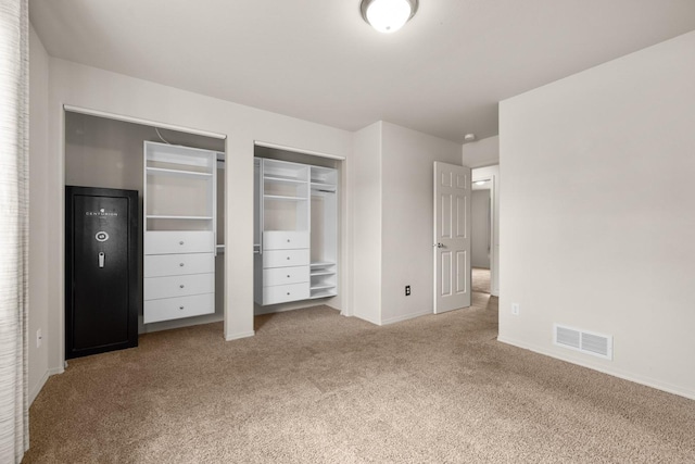 unfurnished bedroom featuring baseboards, multiple closets, visible vents, and carpet