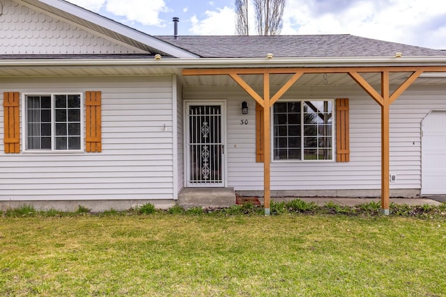 doorway to property with a garage, a shingled roof, and a lawn