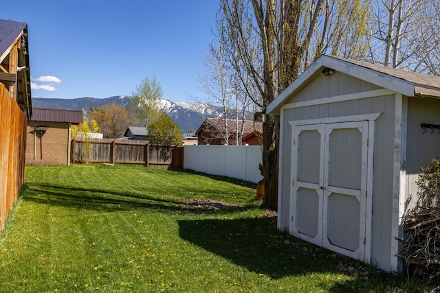 view of yard with a mountain view, an outdoor structure, a fenced backyard, and a shed