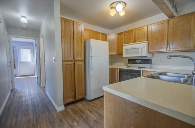 kitchen with baseboards, white appliances, a sink, dark wood-type flooring, and light countertops