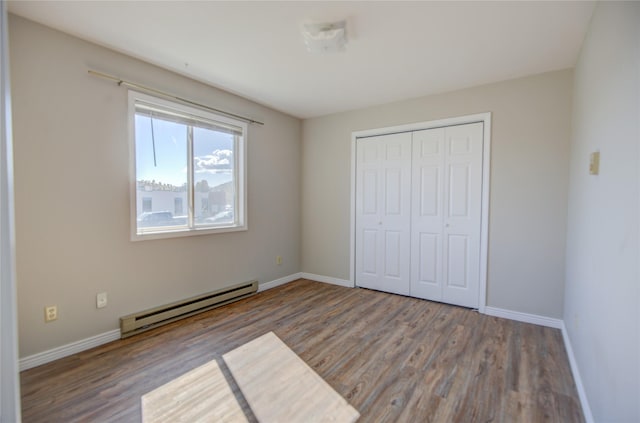 unfurnished bedroom featuring a baseboard radiator, baseboards, and wood finished floors